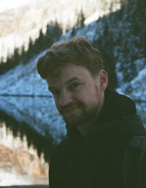 Thomas Bood sitting in front of a lake smilling at the camera